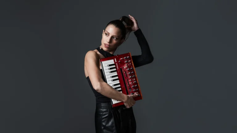 Pianistin Sharon Mansur mit rotem Keyboard vor dunklem Hintergrund